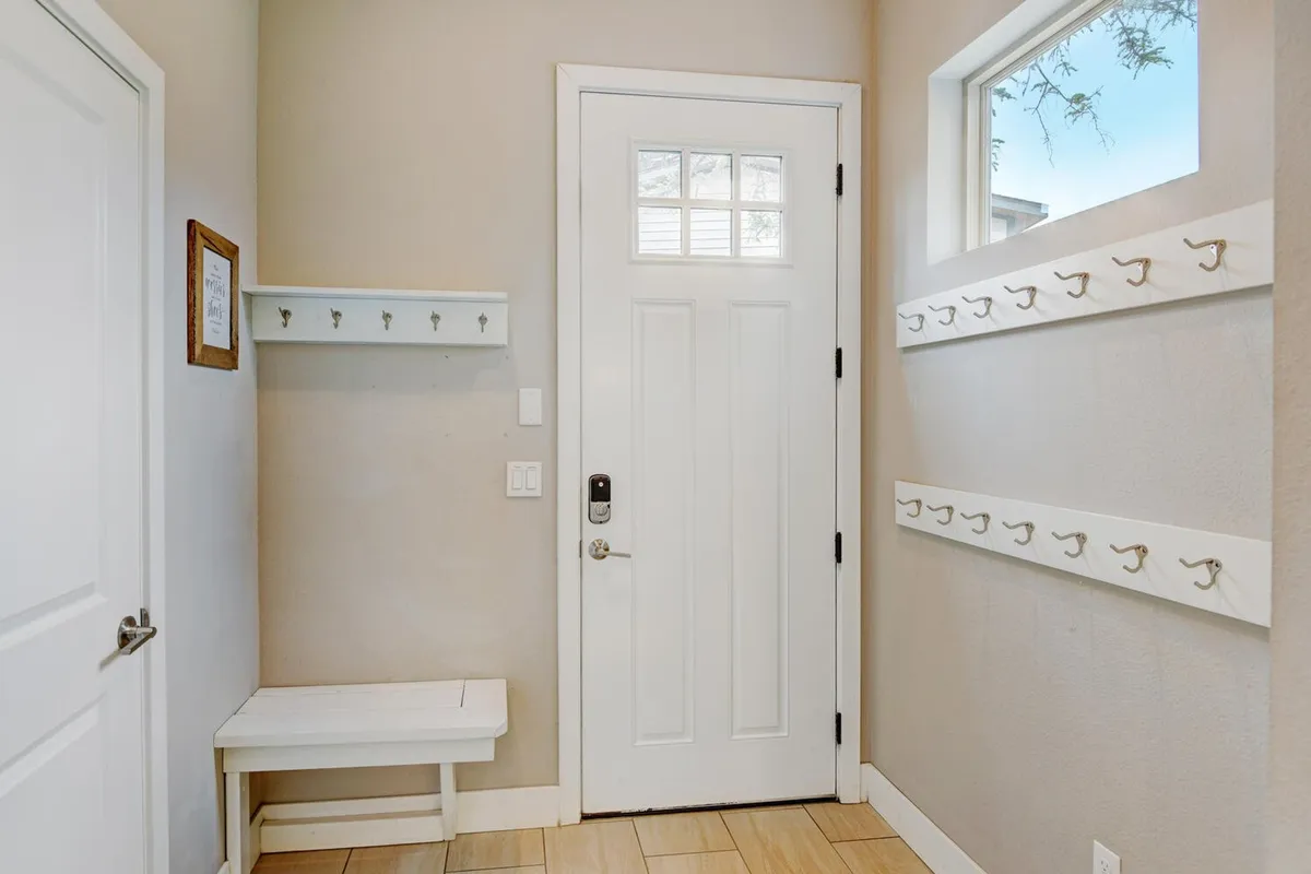 A view of the home's entryway, featuring a front door, coat hooks, and a bench—suggesting the transition from outdoor adventures to a cozy interior.