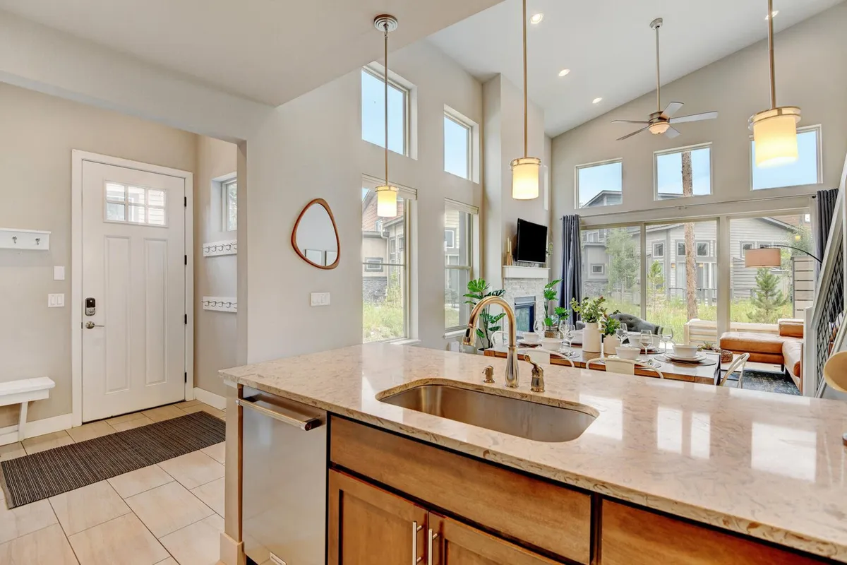A bright, open-concept interior with a kitchen island, dining area, large windows flooding the space with natural light, and comfortable living room seating. The layout encourages both entertaining and tranquil family time, bridging the gap between homey comfort and upscale amenities.