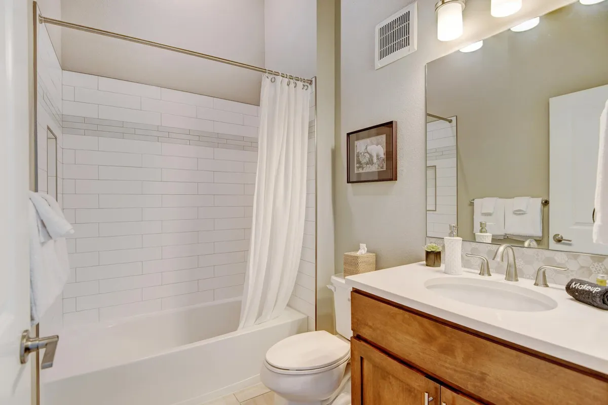 A serene bathroom featuring a luxurious bathtub, vanity, mirror, and tasteful wall art. The ambiance exudes relaxation, ideal for unwinding after an active day outdoors.